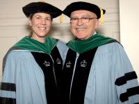 Anne Armstrong-Coben, MD, and Donald Quest, MD, pose for a photo in their academic regalia at Columbia University's medical school graduation in May 2019.